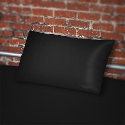 Black pillowcase on black fluidproof sheet against a brick wall