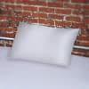 White Fluidproof Pillowcase on white bedsheets set against a brick wall